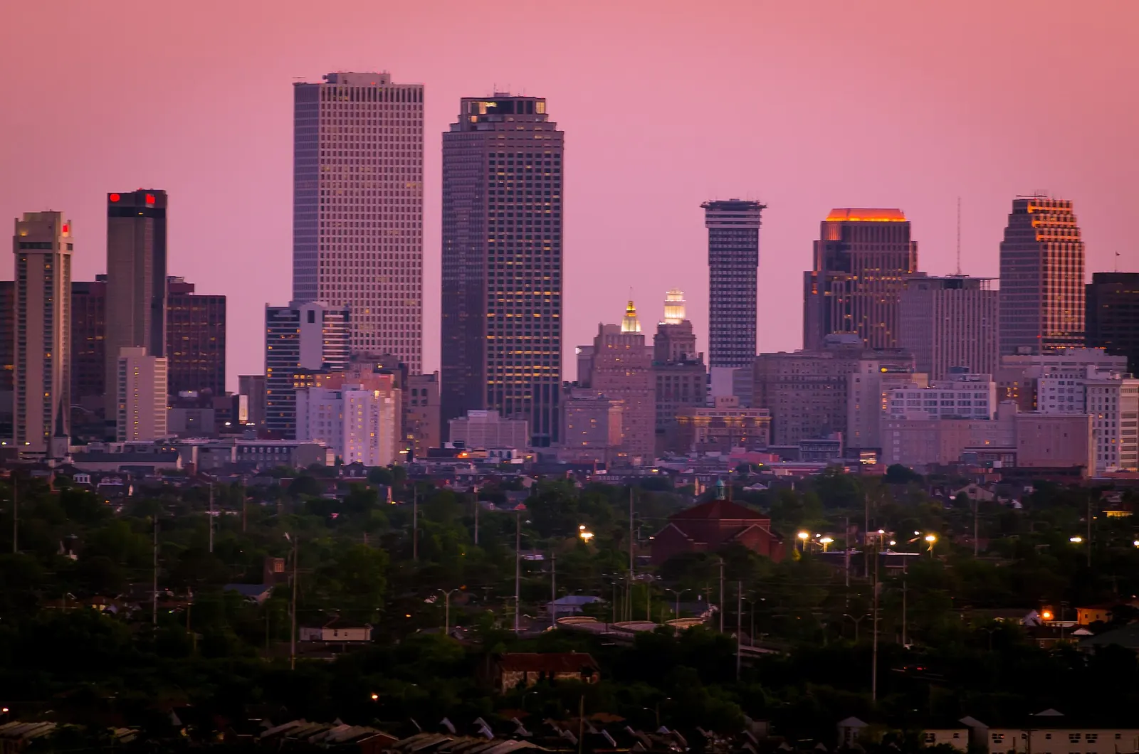 The downtown New Orleans skyline at dusk under a pink sky